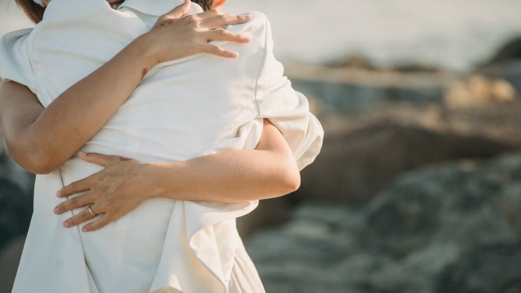 A loving couple shares an intimate embrace by the seaside.